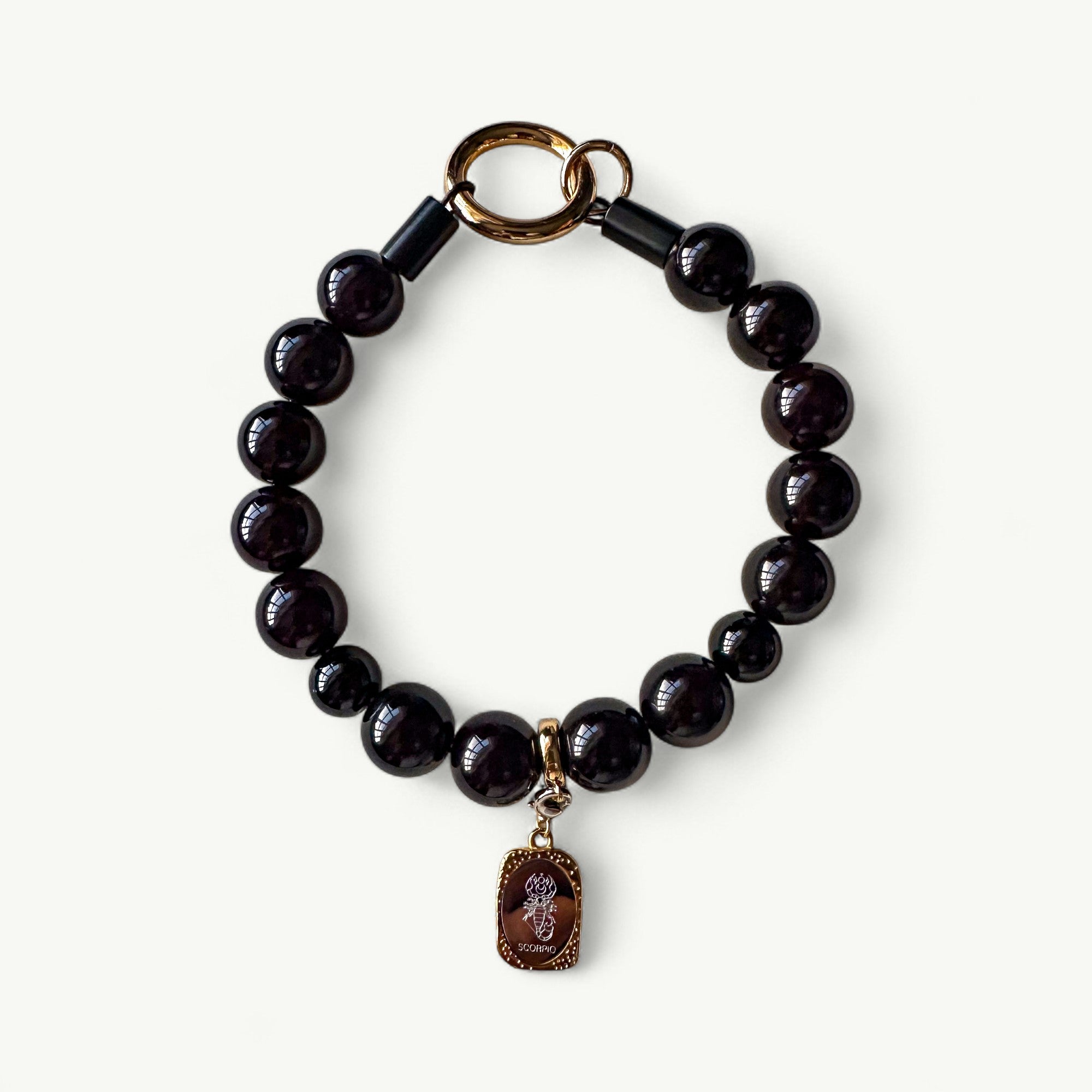 Black beaded collar with a gold charm on a white background