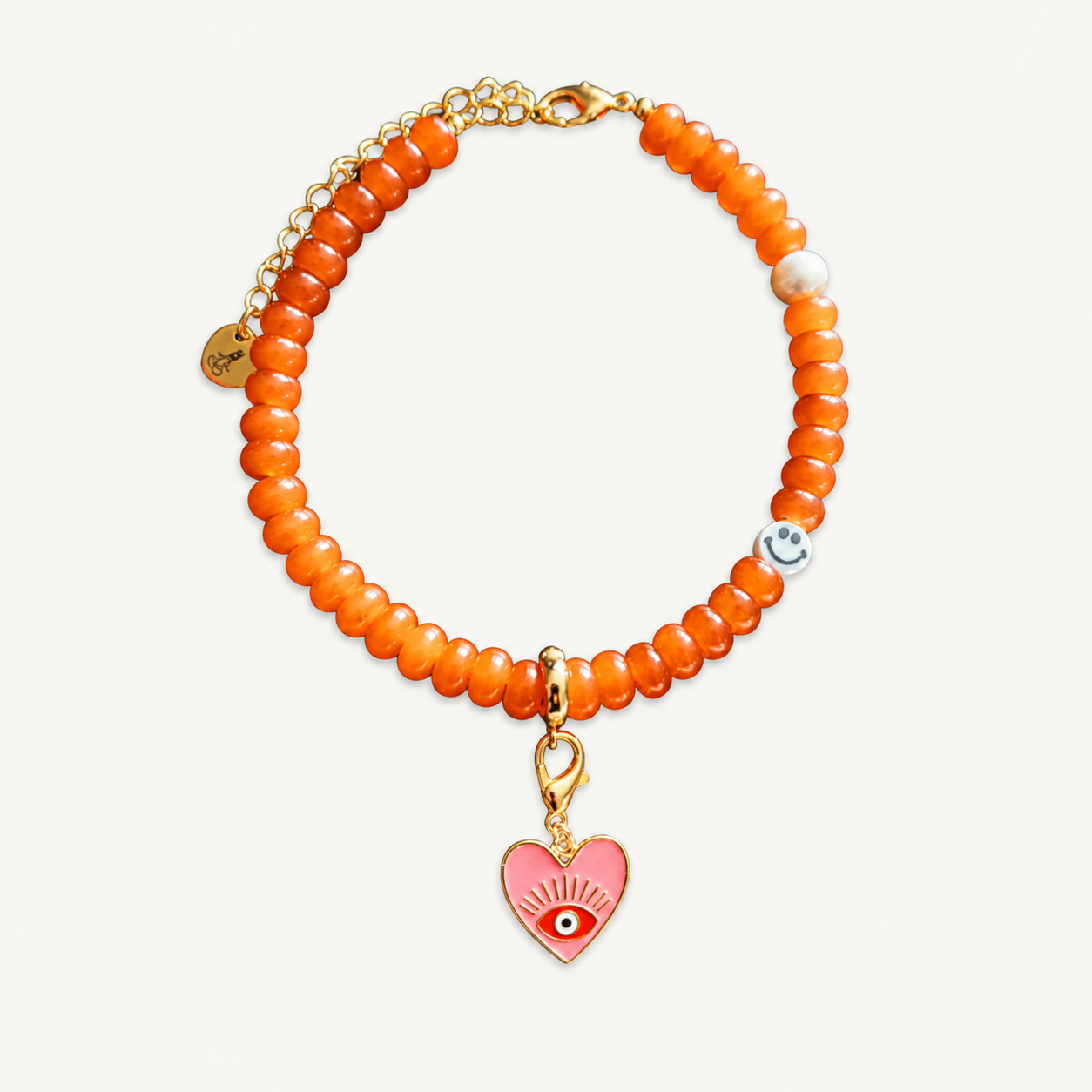 Orange beaded necklace with a pink heart charm on a white background