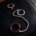 Tortoiseshell silver beaded leash on a black leather ottoman