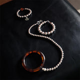 Tortoiseshell silver beaded leash on a black leather ottoman