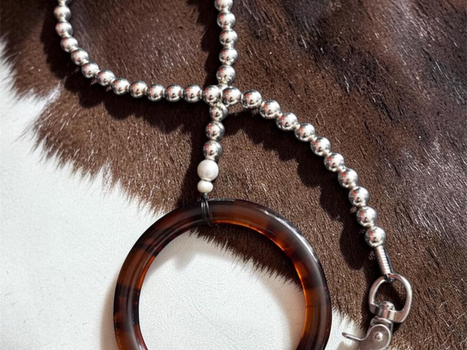 Tortoiseshell silver beaded leash on a cowhide background