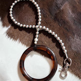 Tortoiseshell silver beaded leash on a cowhide background