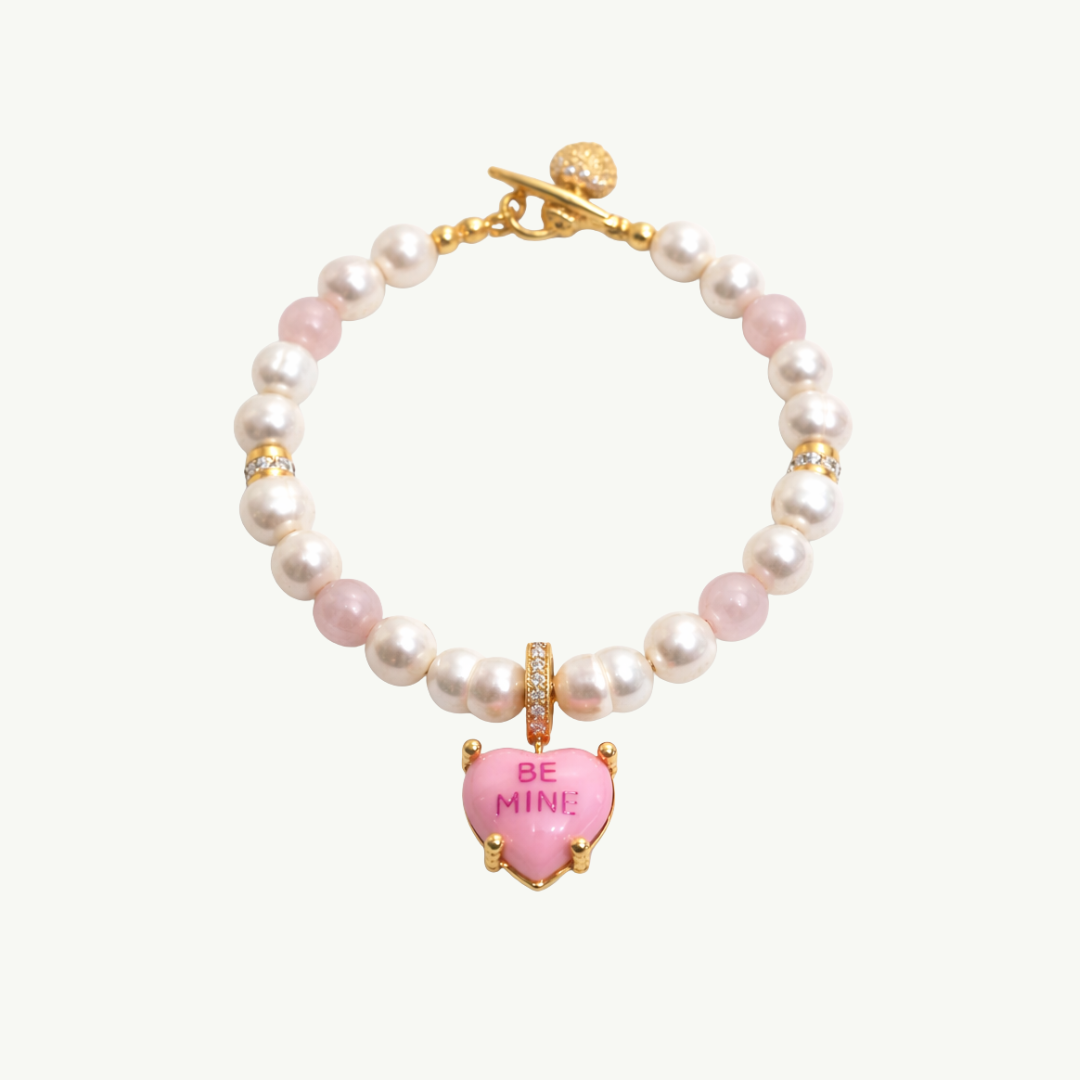 Pearl necklace with pink heart charm and 'BE MINE' text on a white background